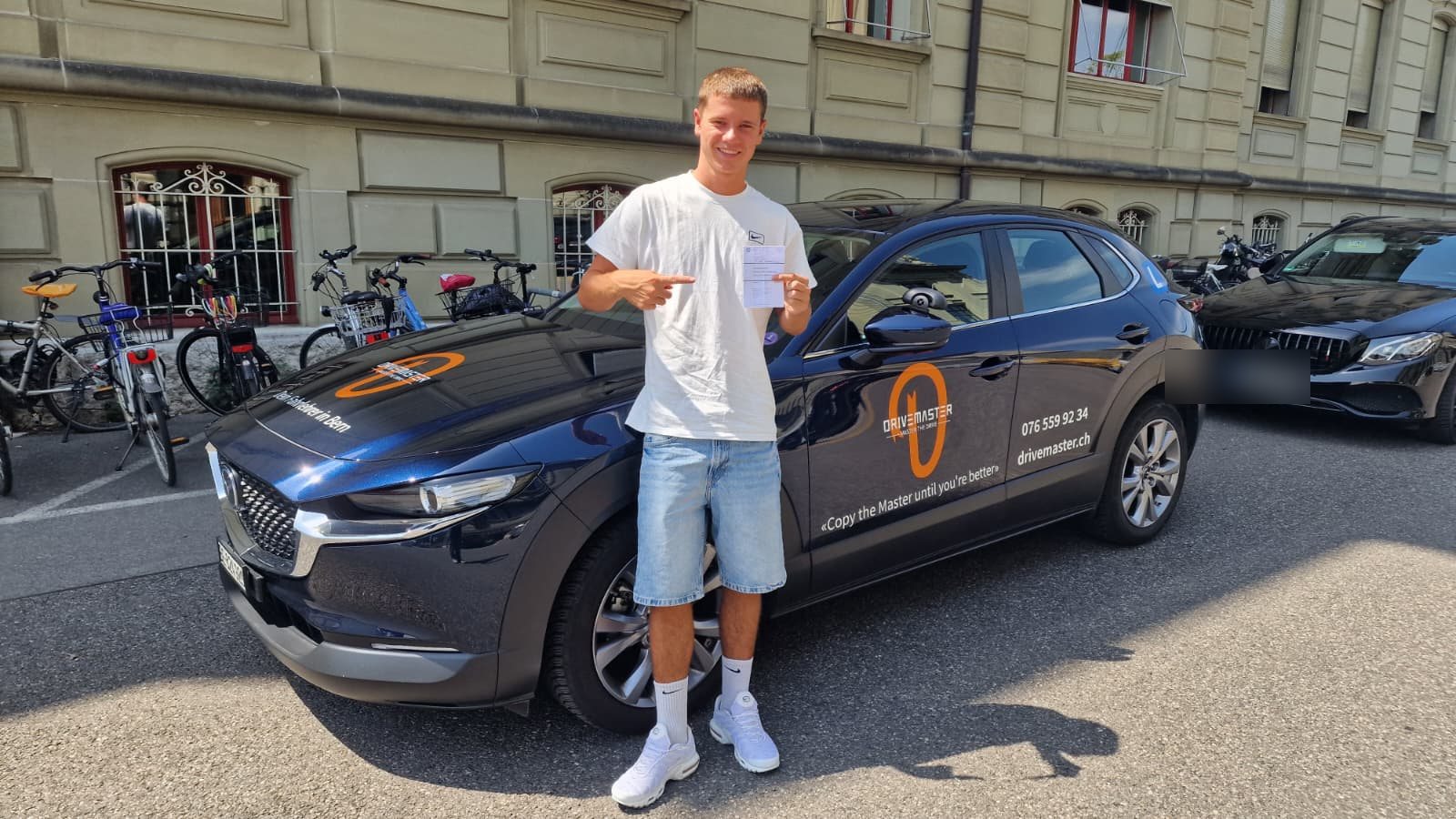Fahrschüler mit bestandener Prüfung beim Drivemaster-Fahrschulauto in Bern