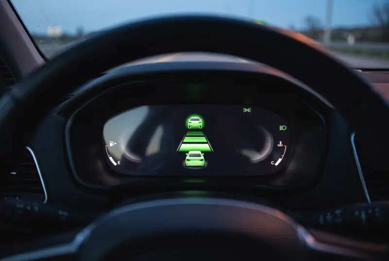 Digitales Kombiinstrument mit grüner Anzeige des Abstandstempomaten: eigenes Auto, Abstandsbalken und erkanntes Fahrzeug davor