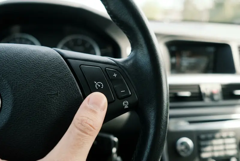 Daumen an den Tempomat-Tasten am Lenkrad: Taste mit Tacho-Symbol, Plus-Minus-Wippe und Taste mit Auto-und-Abstand-Symbol